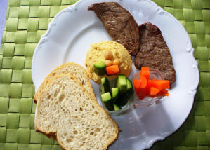 Gegrilltes Fleisch mit Hummus, Fladenbrot und Gemüsesticks